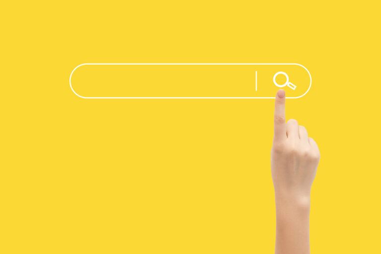Finger presses the search button in the search bar on a yellow background