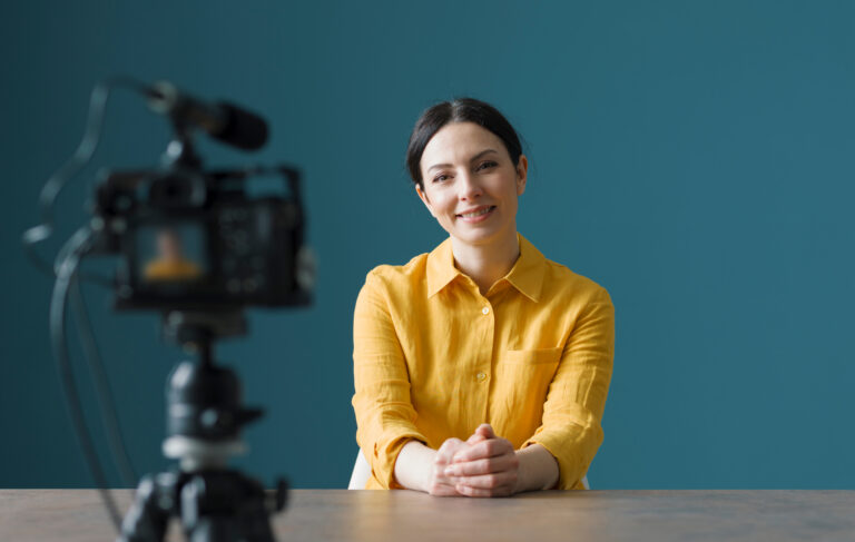 Smiling woman sitting in front of a camera
