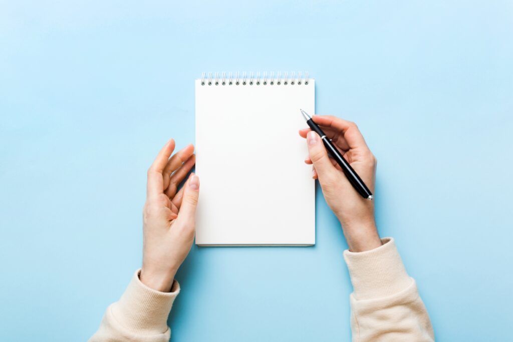 Woman hand with pencil writing on notebook