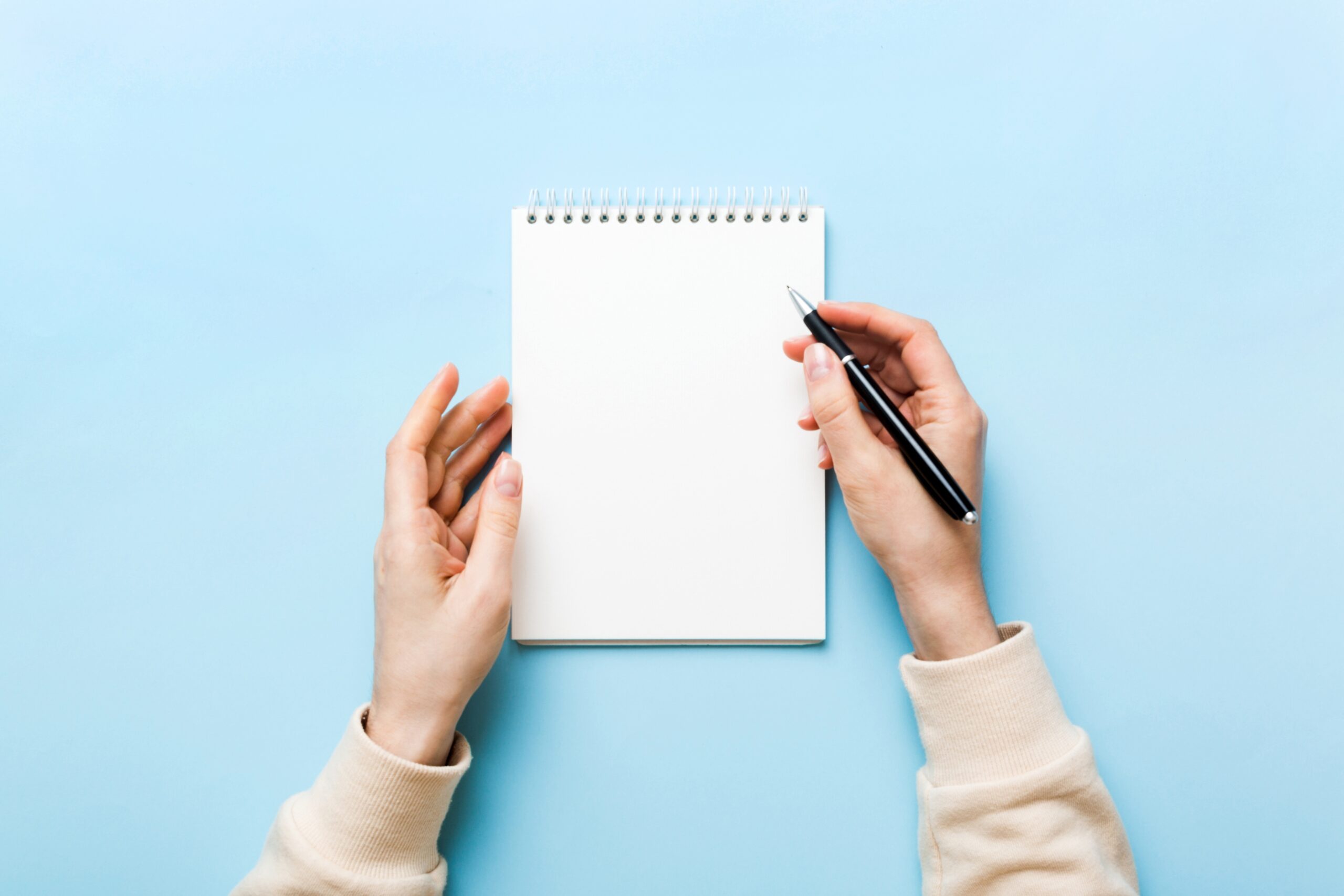 Woman hand with pencil writing on notebook